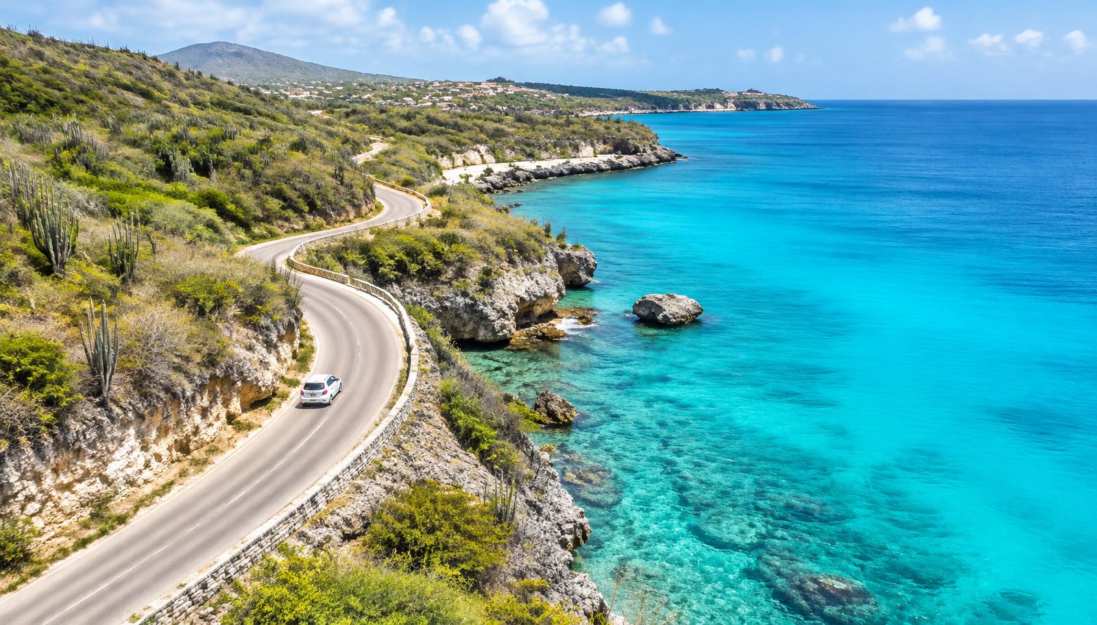 Kustweg langs turquoise zee op Curaçao met een huurauto